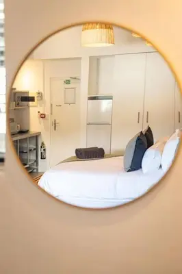 a mirror reflecting a bedroom with a white bed at Studio 7 - Hermanus Waterfront Apartments in Hermanus