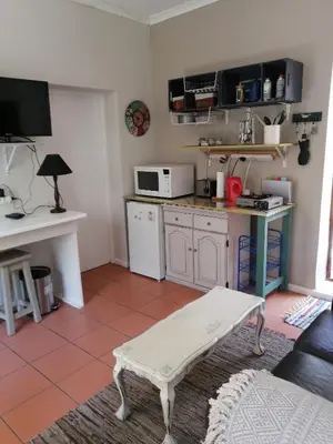 a living room with a kitchen with a table at Voëlklip Garden Flat in Hermanus