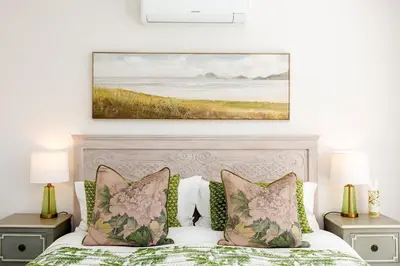 a bedroom with a bed with a painting on the wall at Waddle Inn Luxury apartment in Franschhoek in Franschhoek