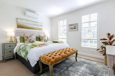 a bedroom with a bed with a ottoman and windows at Waddle Inn Luxury apartment in Franschhoek in Franschhoek