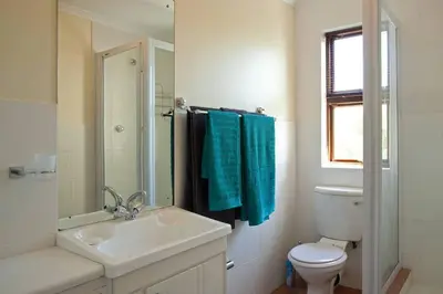 a white bathroom with a sink and a toilet at Luxury Studio sleeps up to 3 adults - Sunset Beach in Cape Town