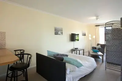 a living room with a couch and a table at Luxury Studio sleeps up to 3 adults - Sunset Beach in Cape Town