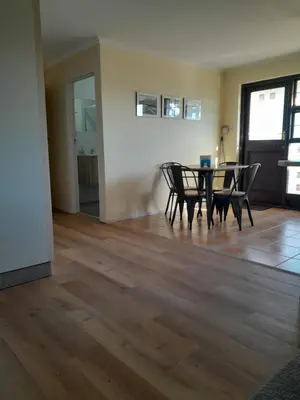 a dining room with a table and chairs on a wooden floor at Luxury Studio sleeps up to 3 adults - Sunset Beach in Cape Town