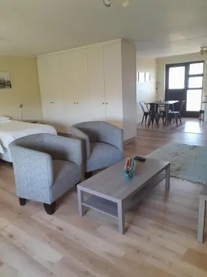 a living room with two chairs and a coffee table at Luxury Studio sleeps up to 3 adults - Sunset Beach in Cape Town