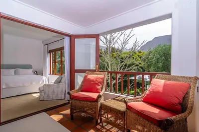 a room with a balcony with chairs and a bed at Fynbos House in Hermanus