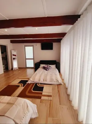 a bedroom with a bed with curtains and a wooden floor at Villa Rosa Luxury in Cape Town