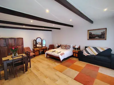 a bedroom with a bed and a couch and a table at Villa Rosa Luxury in Cape Town