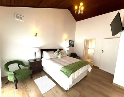 a bedroom with a large bed and a chair at Villa Rosa Luxury in Cape Town