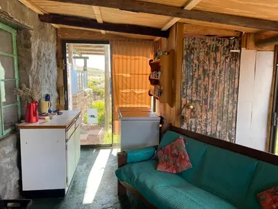a living room with a green couch and a kitchen at Skuilkrans Private Nature Reserve in McGregor