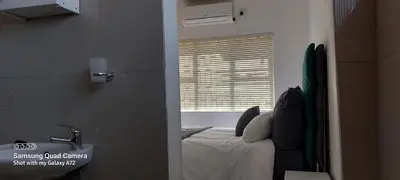 a bedroom with a bed and a sink and a window at COMFORT LODGE milnerton, Cape Town in Cape Town