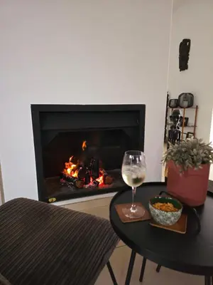 a glass of wine on a table in front of a fireplace at Die Regte Rede in Cape Town