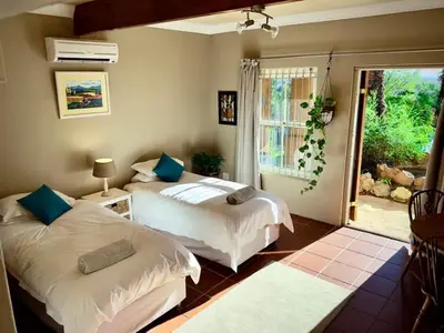 two beds in a room with a window at Guest Suite in Tuscan Farmhouse in Paarl
