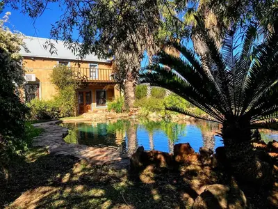 a house with a pond in front of a building at Guest Suite in Tuscan Farmhouse in Paarl