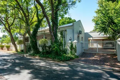 a house with a fence and trees on a street at Beautiful country house set in lush garden in Wellington