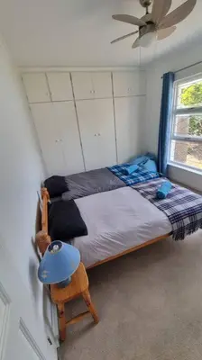 a bedroom with a bed and a chair and a window at Beautiful 4 bedroom home overlooking the ocean in Somerset West Cape Town in Cape Town
