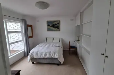 a white bedroom with a bed and a window at Beautiful 4 bedroom home overlooking the ocean in Somerset West Cape Town in Cape Town
