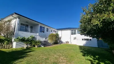 a large white house with a grass yard at Beautiful 4 bedroom home overlooking the ocean in Somerset West Cape Town in Cape Town