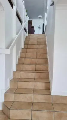 a staircase in a house with wooden floors and white walls at Beautiful 4 bedroom home overlooking the ocean in Somerset West Cape Town in Cape Town