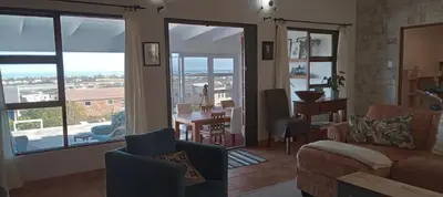 a living room with a couch and chairs and a balcony at Red Disa in Malkopvlei