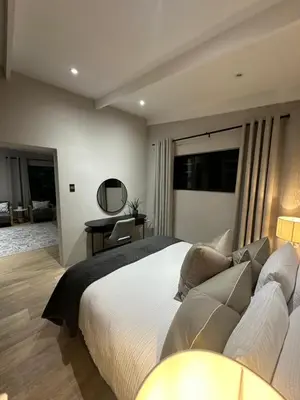 a bedroom with a large bed and a desk at Somerset-West PRIME SPOT- Solar Powered! in Cape Town