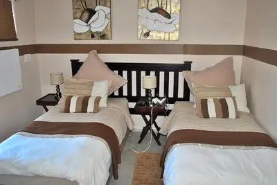 a bedroom with two beds and a table with lamps at Delash Pine Villa in Cape Town