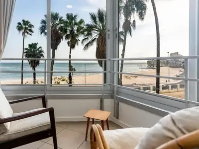 a living room with a view of the beach and palm trees at Elana Beachfront Condo in Strand