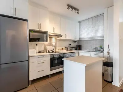 a kitchen with white cabinets and a stainless steel refrigerator at Elana Beachfront Condo in Strand