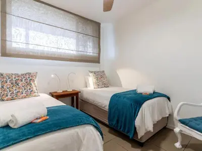a bedroom with two beds and a window at Elana Beachfront Condo in Strand