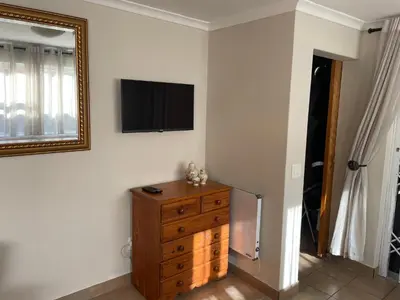 a room with a dresser and a television on a wall at Morrison Hotel in Parklands