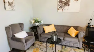 a living room with two couches and a table at Big6 Guesthouse in Somerset West