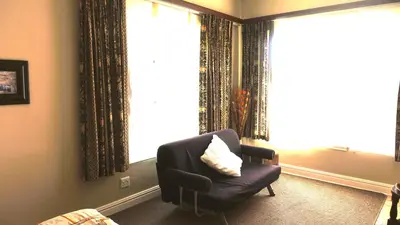 a living room with a chair and a large window at Big6 Guesthouse in Somerset West