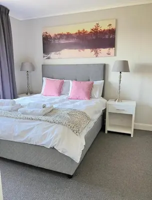 a bedroom with a large bed with pink pillows at Stylish waters edge apartment in Cape Town