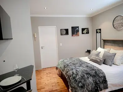 a bedroom with a bed and a table and a clock at Royal Boland in Paarl