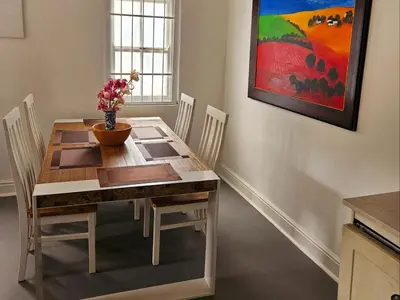 a dining room table with chairs and a vase with flowers at PinotageLuxuryCollection 9A Herte Suite in Stellenbosch
