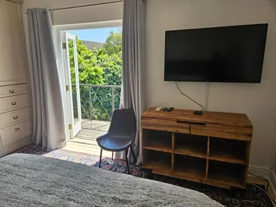 a bedroom with a television and a dresser with a chair at PinotageLuxuryCollection 9A Herte Suite in Stellenbosch
