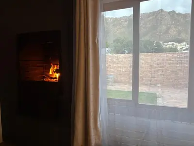 a fireplace in a window with a view of a mountain at Mountain Views, beach walks, heart of old village in Gordonʼs Bay
