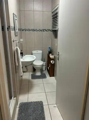 a bathroom with a white toilet and a sink at Holihome in Brackenfell