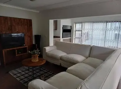 a living room with a white couch and a television at Holihome in Brackenfell