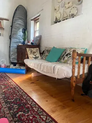 a room with a bed and a table and a rug at Awesome room in surf house in Hermanus