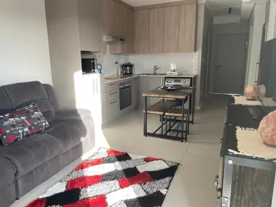 a living room with a couch and a table in a kitchen at Rozama's little nest in Cape Town