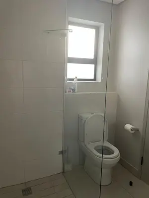 a white bathroom with a toilet and a window at Rozama's little nest in Cape Town