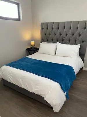 a bedroom with a large bed with a blue blanket at Rozama's little nest in Cape Town