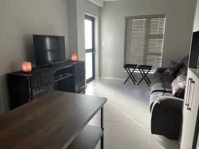 a living room with a couch and a flat screen tv at Rozama's little nest in Cape Town