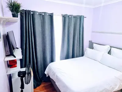 a bedroom with a bed and a window with curtains at 3 bedroom garden house in Tableview in Table View