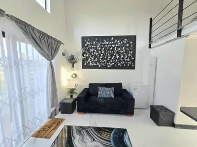 a living room with a black couch and a window at Aqua Breeze in Cape Town