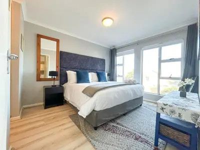 a bedroom with a large bed and a large window at Century Hideaway with Mountain views, Security, FREE Parking in Cape Town