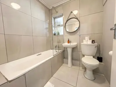 a white bathroom with a toilet and a sink at Century Hideaway with Mountain views, Security, FREE Parking in Cape Town