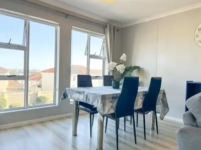 a dining room with a table and chairs and windows at Century Hideaway with Mountain views, Security, FREE Parking in Cape Town