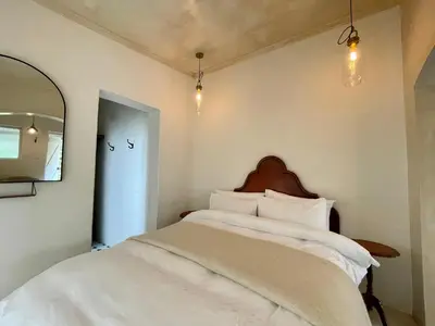 a bedroom with a bed with white sheets and a mirror at La Rose Quartier in Wellington