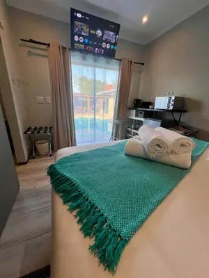 a bedroom with a bed with a green blanket on it at Tehillah on Boom in Bothasig